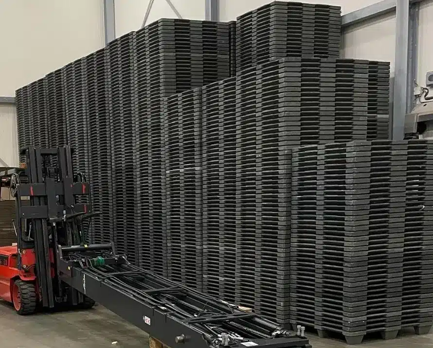 Heftruck bij hoge stapels kunststof pallets in een loods